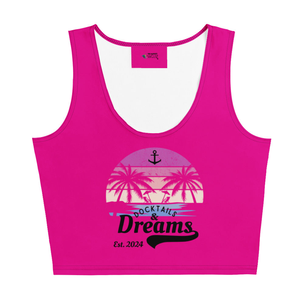 The Naughty Angler™ pink women’s crop top featuring the “Docktails and Dreams” black front lettering in regular and cursive fonts, with a back design showing a palm-tree beach scene in a pink, peach, and blue gradient and a small peach signature reading “The Naughty Angler Clothing Co.”