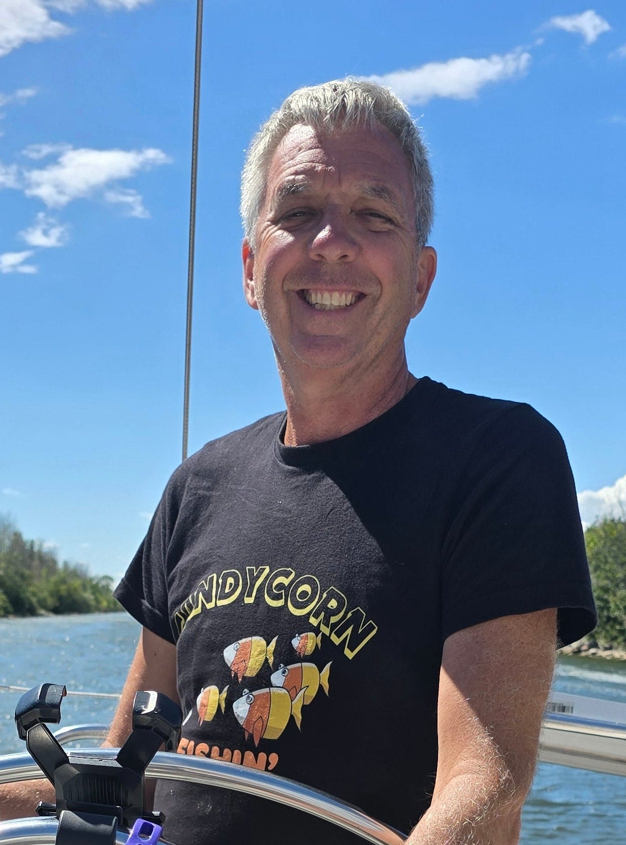 Graham smiling aboard SV Naughty Angler during sailing adventures, wearing a medium Candy Corn Fishin’ unisex T-shirt from The Naughty Angler™.